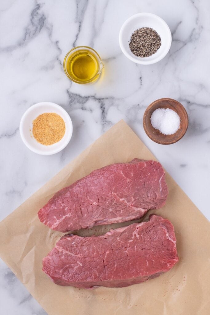 Ingredients for grilled sirloin steak: sirloin steaks, olive oil, salt, black pepper, and garlic powder.