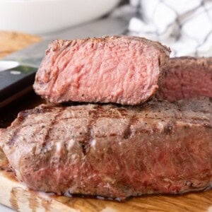 Two steaks stacked on top of each other. The top steak is sliced in half to show the interior.