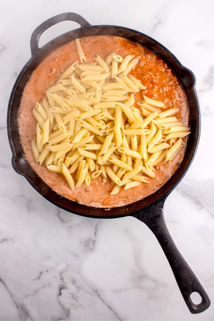 Cooked penne pasta added to the red sauce.