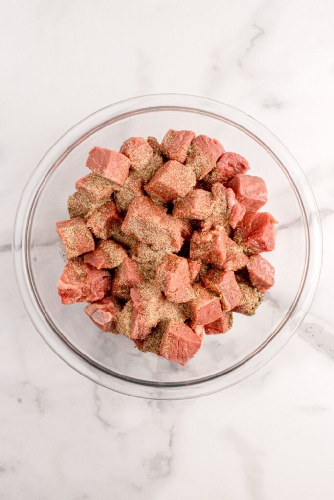 Raw steak cubes seasoned with salt, pepper, garlic powder, onion powder, Italian seasoning, and smoked paprika.