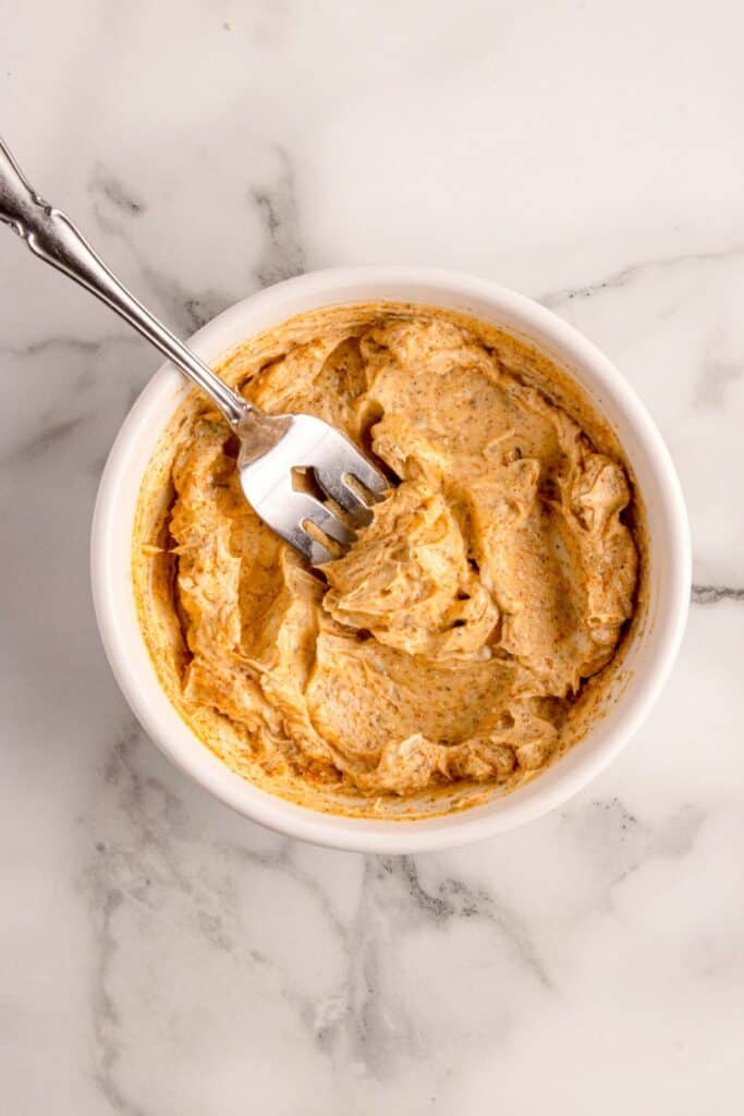 A white bowl with butter and seasonings mixed together.