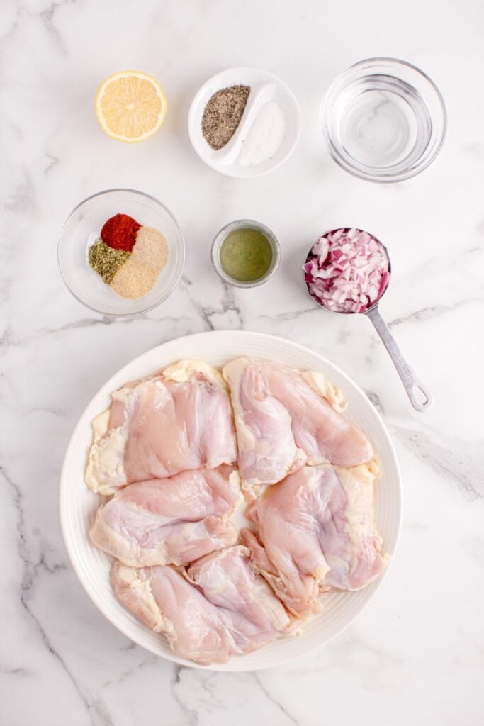 Ingredients for slow cooker chicken thighs: skinless chicken thighs, onion, water, lemon juice, neutral cooking oil, garlic powder, onion powder, paprika, Italian seasoning, salt, and black pepper