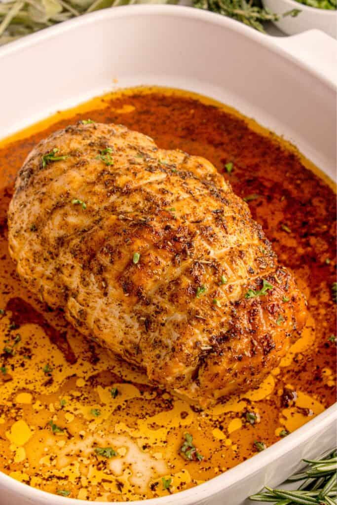 White square baking dish with cooked turkey breast.