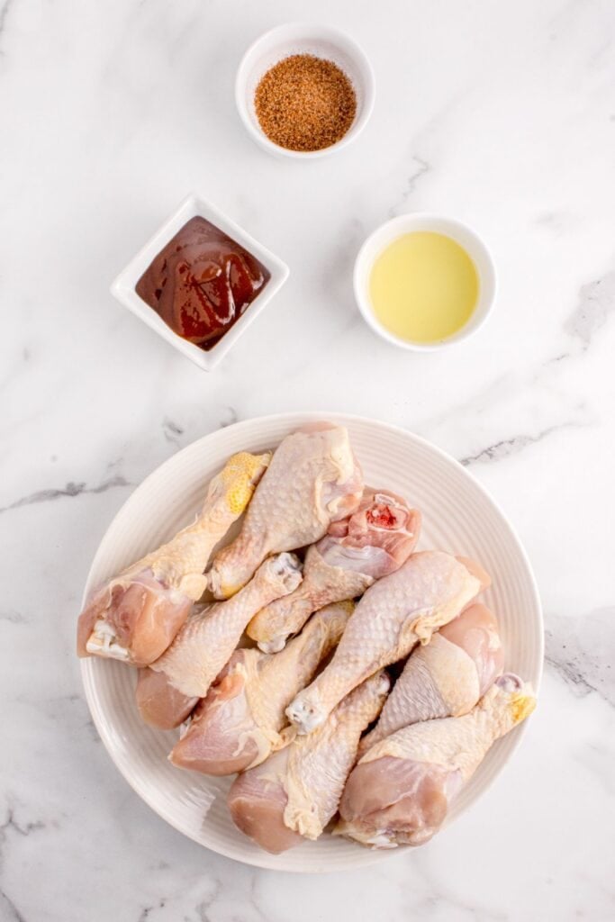 Ingredients for grilled chicken legs: chicken drumsticks, BBQ sauce, olive oil, store bought spice rub (like Slap Ya Mama).