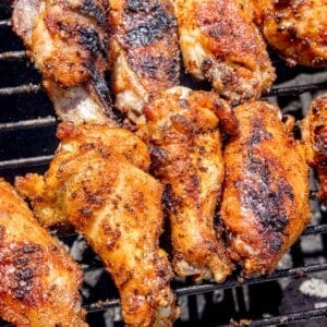 Chicken wings cooking over a charcoal grill.