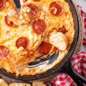 Pizza dip with crostini pieces around the cast iron pan.