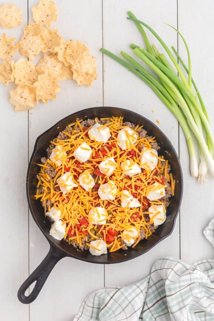 Cast iron pan layered with sausage cream cheese dip ingredients.
