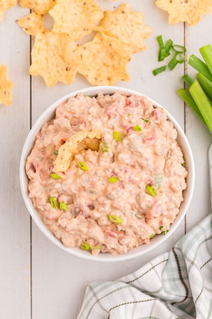 White bowl of sausage cream cheese dip surrounded by tortilla chips.
