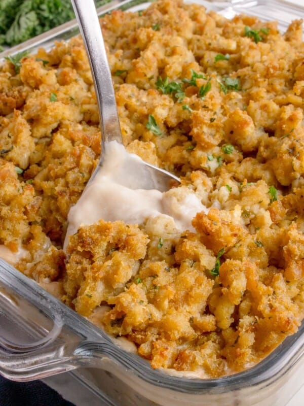 A serving spoon is scooping out a helping of casserole.