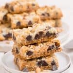 Stack of three 7 layer bars on a white plate.