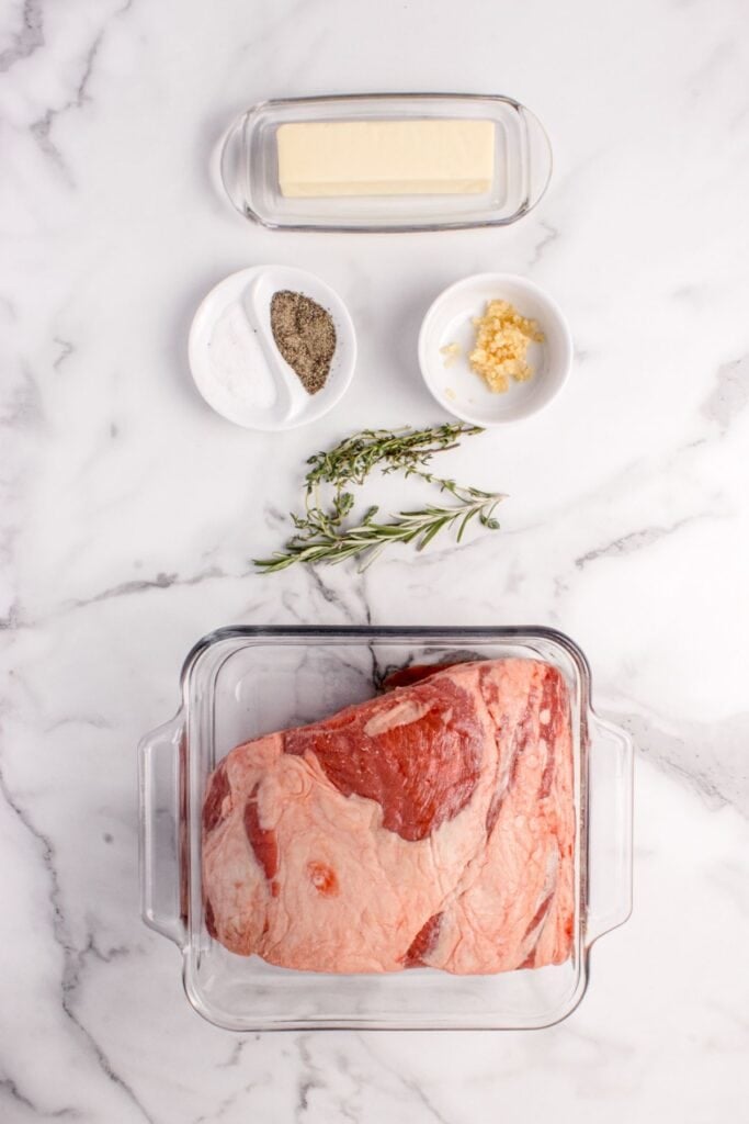 Ingredients for boneless prime rib: prime rib cut, unsalted butter, fresh rosemary, fresh thyme, garlic, salt, and ground black pepper.
