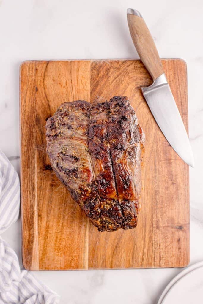Completed prime rib resting on a wooden cutting board.