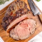 Sliced prime rib on a wooden cutting board.