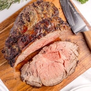 Sliced prime rib on a wooden cutting board.