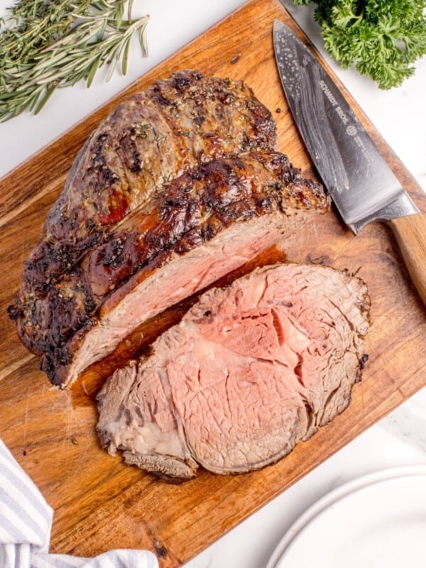 Sliced prime rib on a wooden cutting board.
