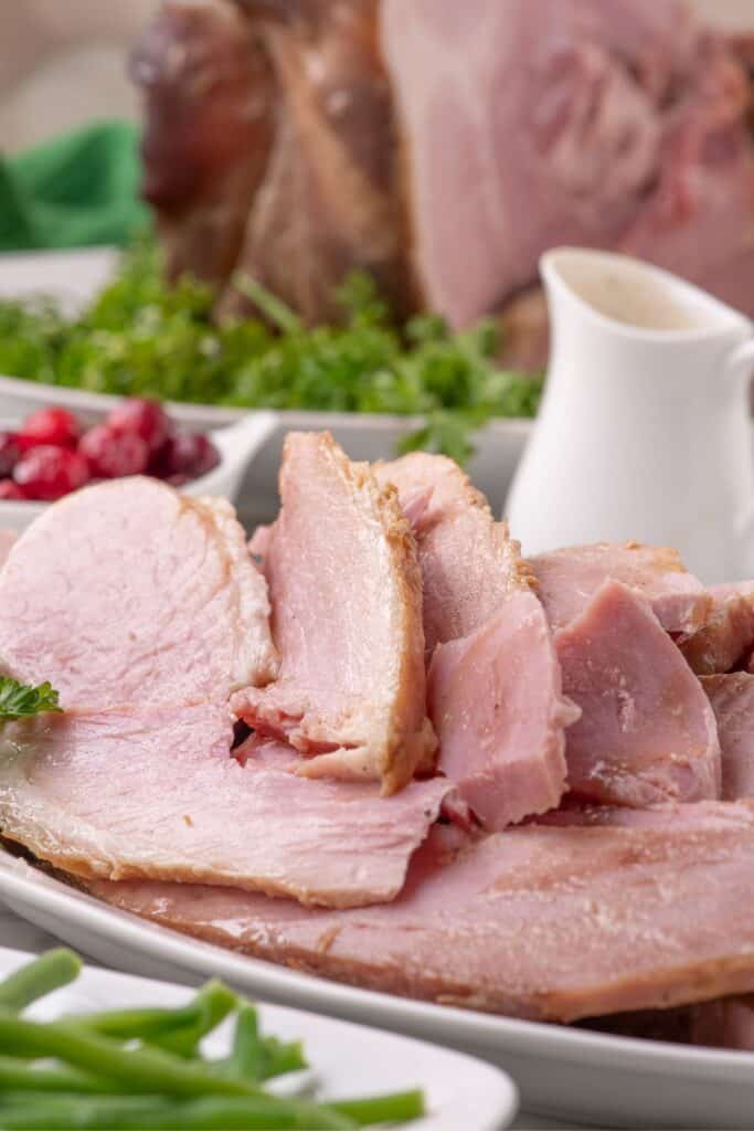 Slices of ham on a white dinner platter.