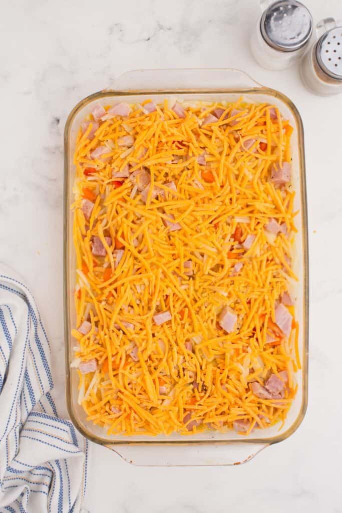 Egg casserole is topped with shredded cheese before baking.
