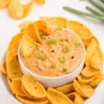 Rotel cheese dip in a white bowl surrounded by a plate of corn chips.
