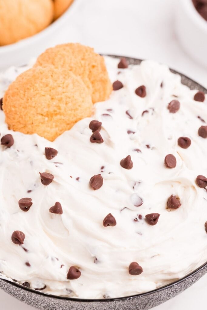 Completed cookie dough dip in a bowl with two vanilla cookies nestled into it.