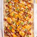 Pulled pork nachos on a aluminum foil covered baking sheet.