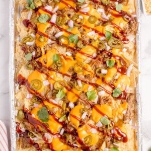 Pulled pork nachos on a aluminum foil covered baking sheet.