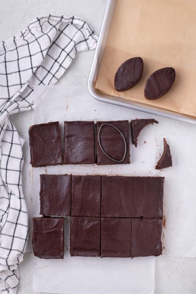 Brownies have been removed from the pan and sliced into 12 rectangles. A Football shaped cookie cutter is used to cut the football shape out of the rectangles.