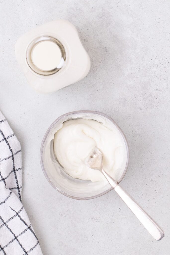 A small glass bowl with powdered sugar and cream whisked together with a fork to create the white icing.