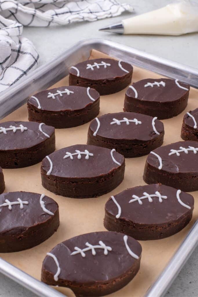 A parchment lined baking sheet with completed football brownies on it.