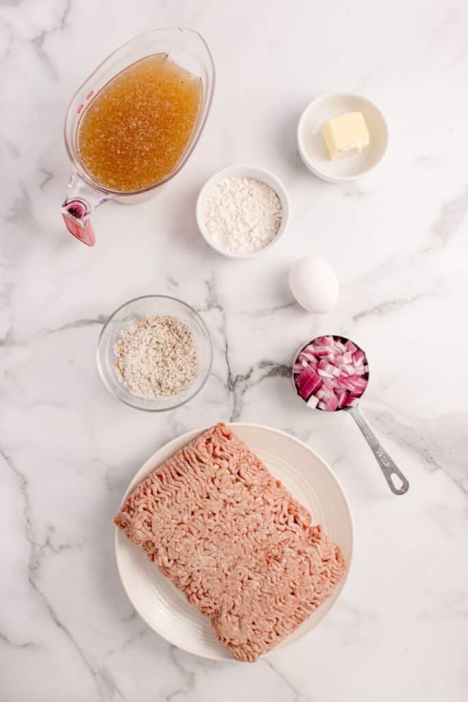Ingredients for meatballs with gravy: ground beef, egg, onion soup mix, red onion, flour, butter, and beef broth.