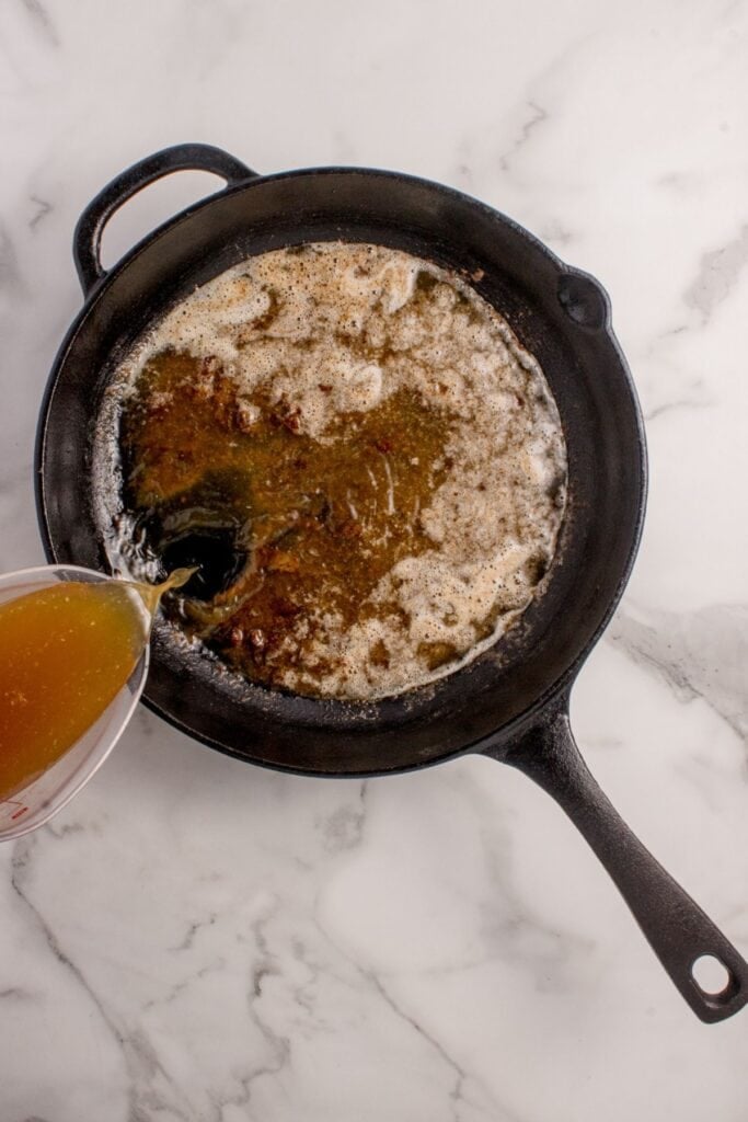 Beef broth added to cast iron pan to create a gravy.