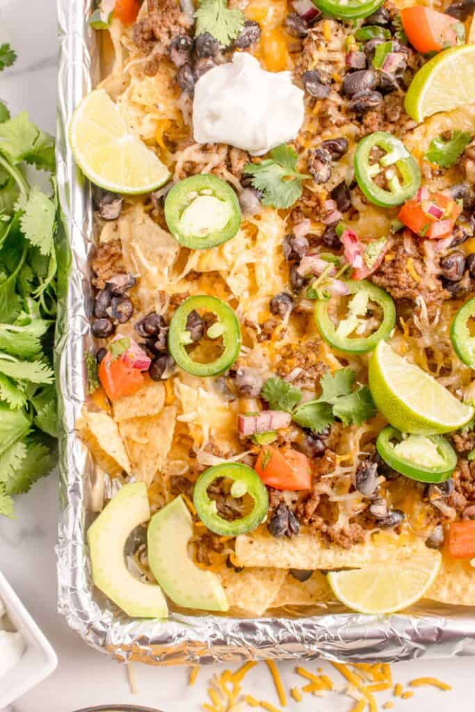 Completed oven nachos on an aluminum foil covered baking sheet.