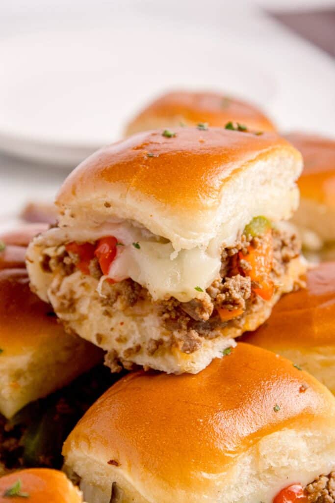 A philly cheesesteak slider stacked on top of sliced sliders.