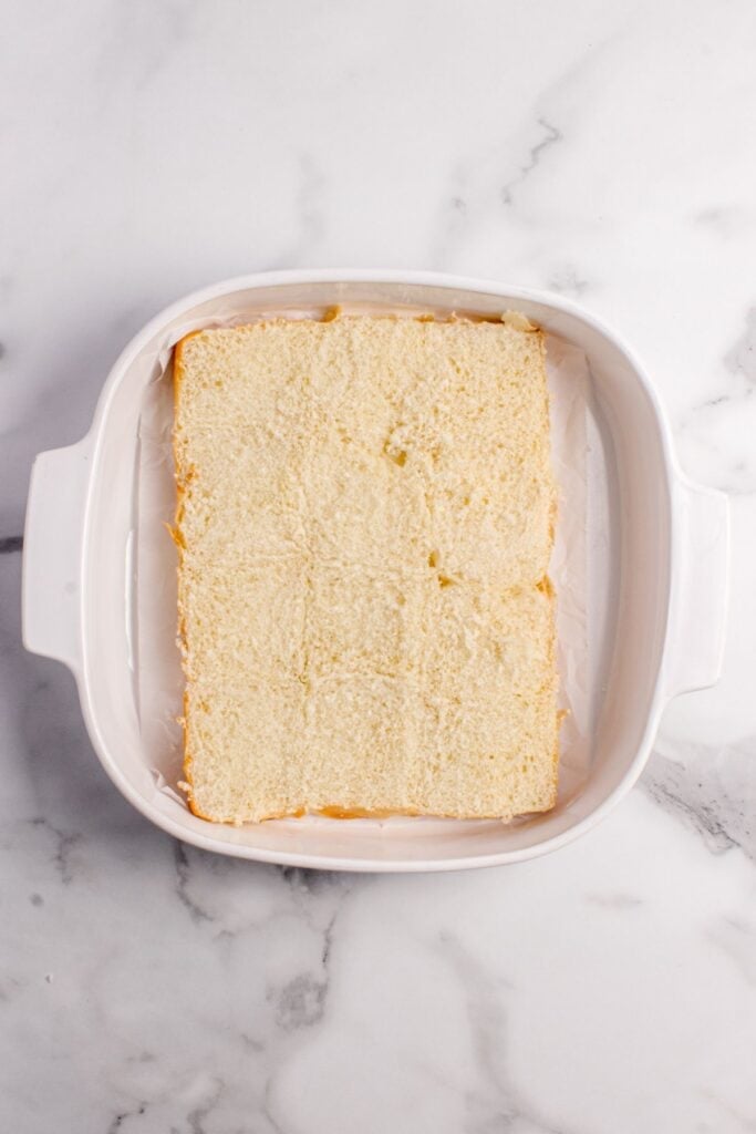 White baking pan with sliced hawaiian rolls in the bottom of it.