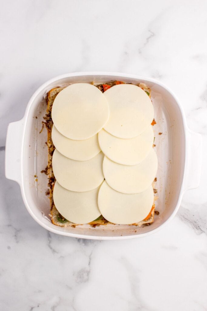 Cheesesteak sliders topped with provolone cheese slices.