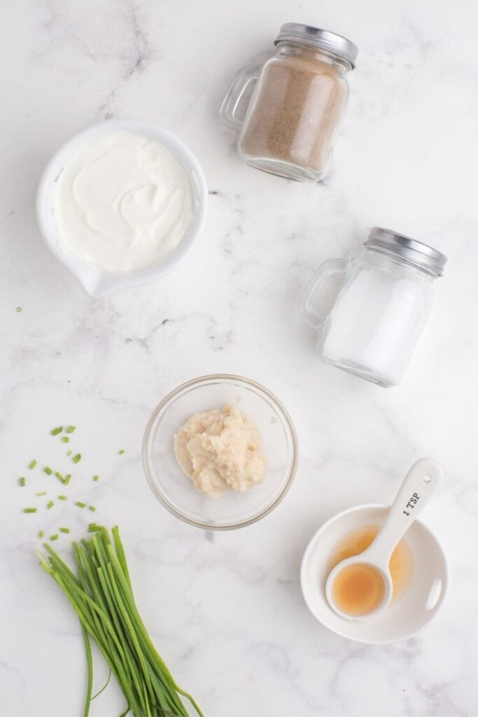 Ingredients for horseradish sauce: Sour cream, horseradish, apple cider vinegar, salt, pepper, and chives.