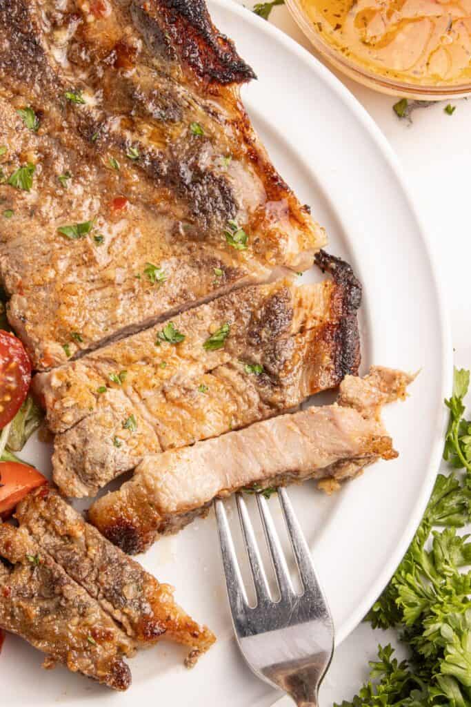 Sliced pork steaks on a white dinner plate.
