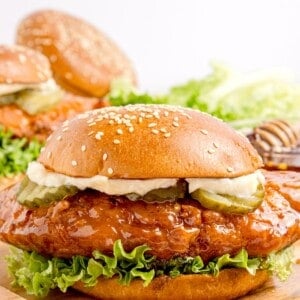 Completed hot honey chicken sandwich on a wooden cutting board.