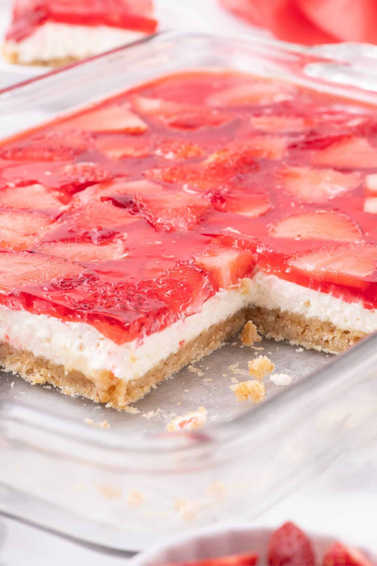 Sidelong view of sliced strawberry pretzel salad in a glass baking dish to show the layers.