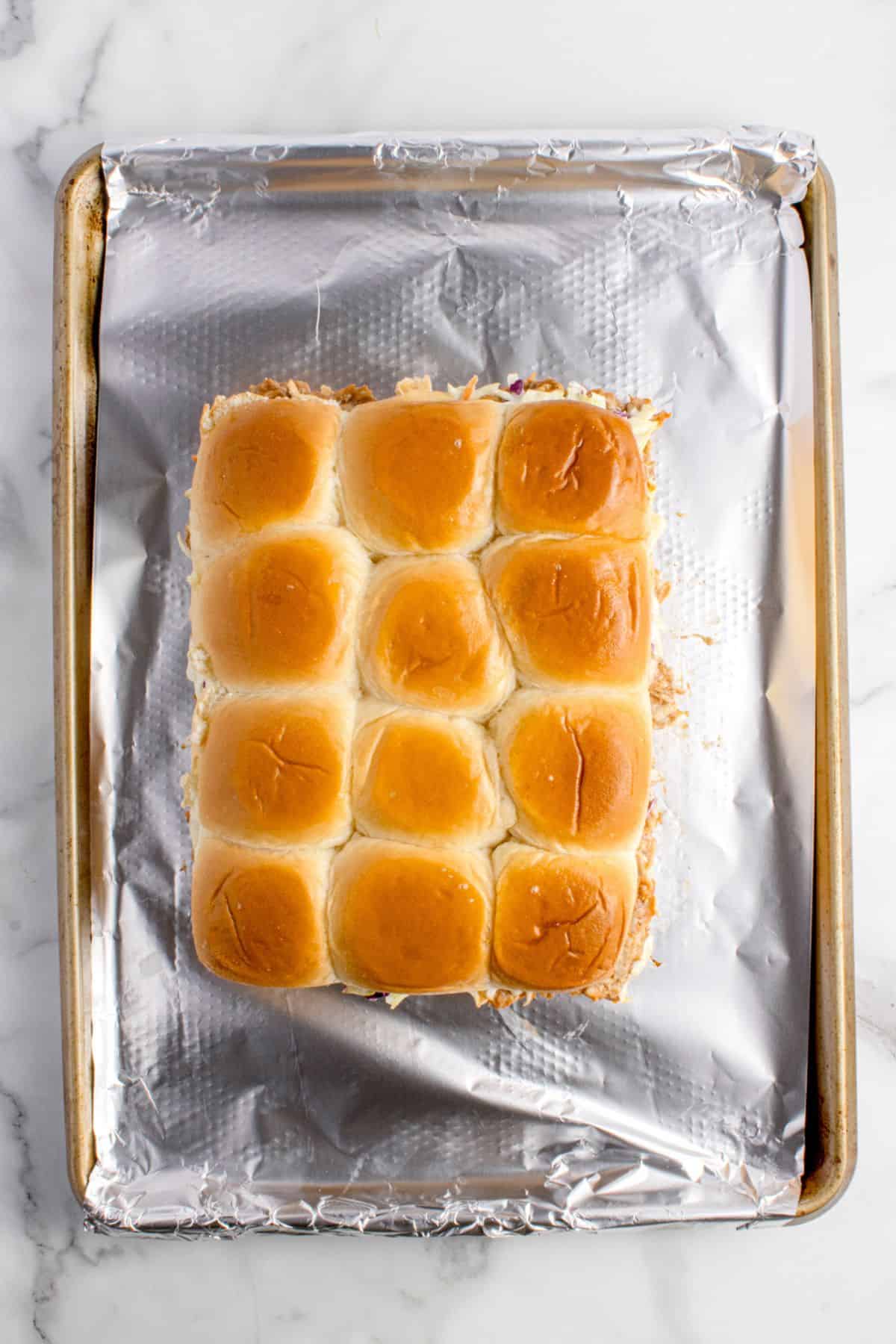 BBQ chicken slides are placed on a aluminum foil covered baking sheet.