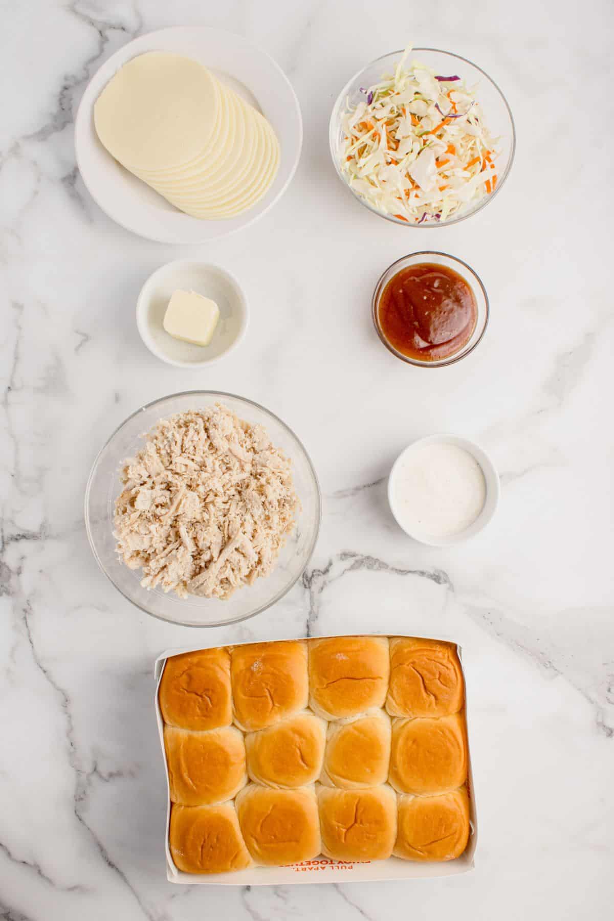 Ingredients for BBQ chicken sliders: Hawaiian rolls, chicken, barbecue sauce, provolone cheese, coleslaw mix, ranch dressing, and butter.