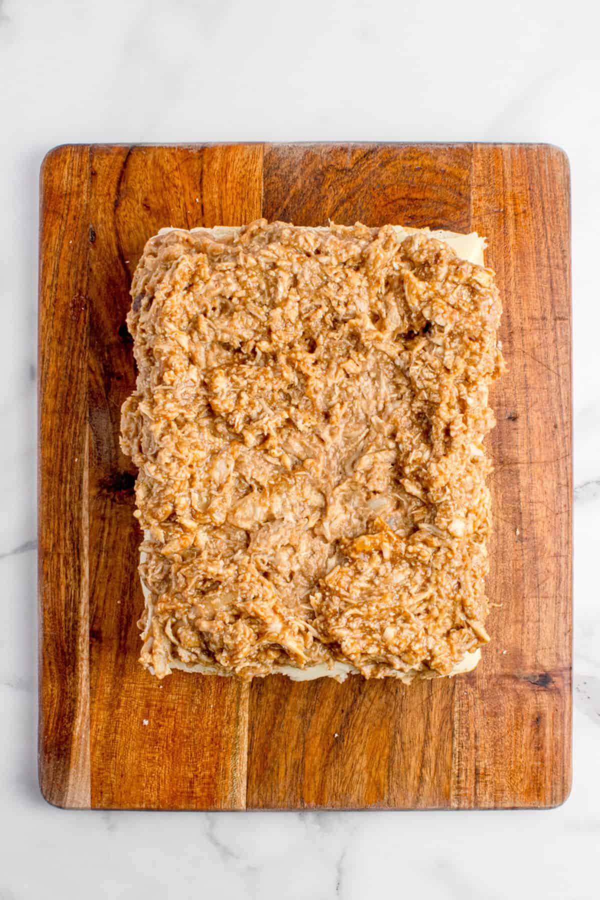 A layer of BBQ chicken is placed on top of the cheese layer.