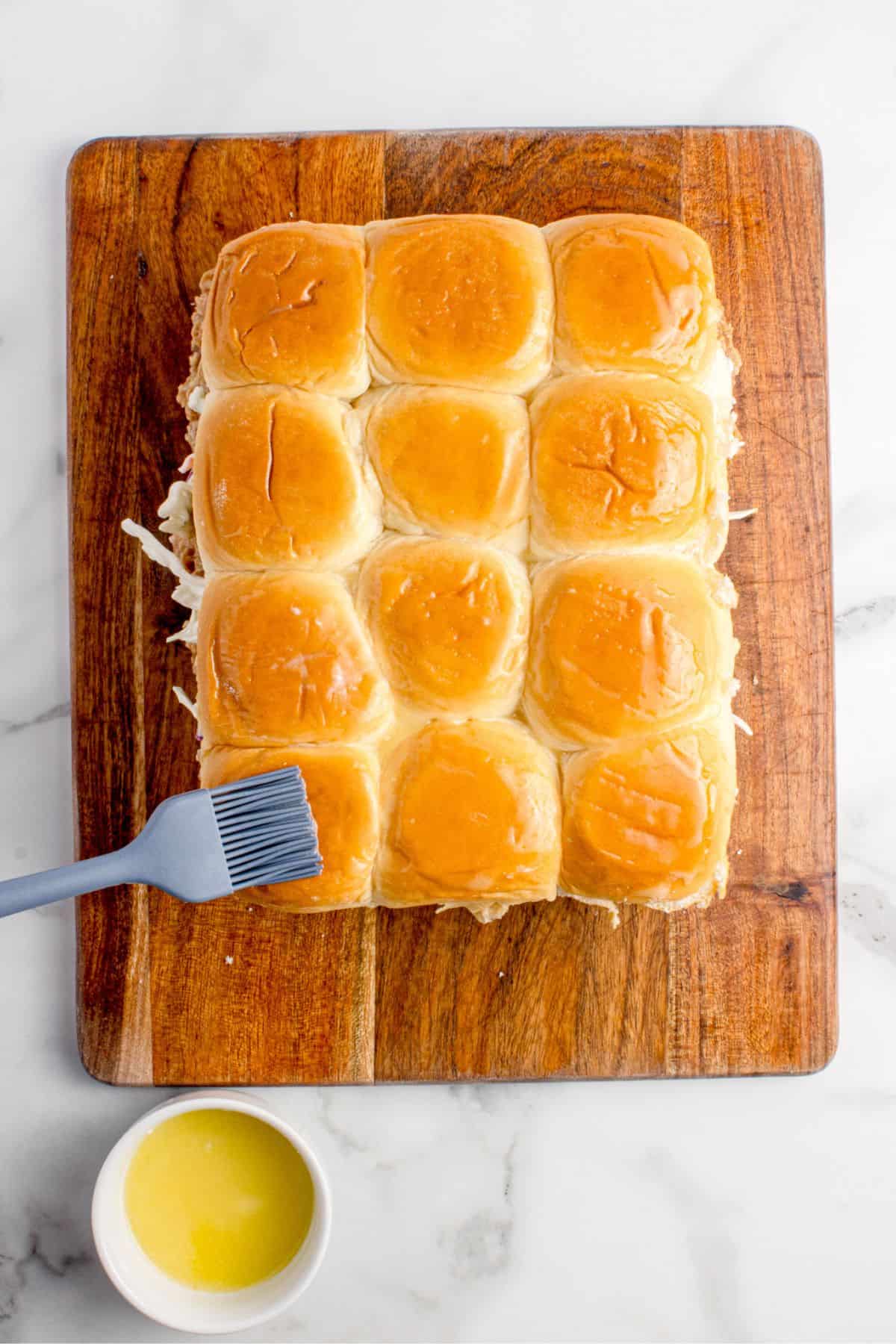 The sandwiches are completed with the top half of the buns and then brushed with melted butter.
