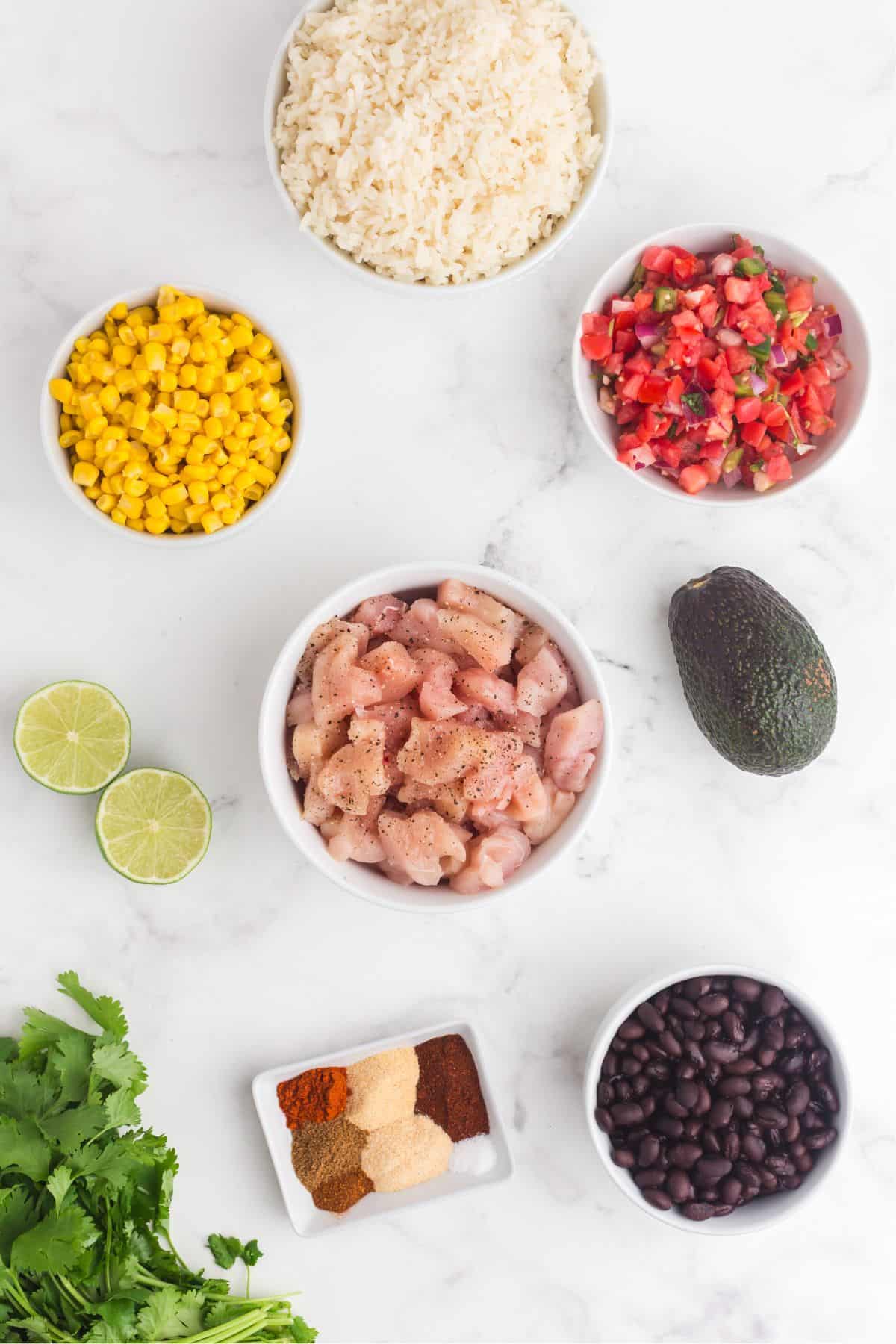 Ingredients for chicken burrito bowls: chicken breast, chili powder, onion powder, garlic powder, paprika, cumin, sugar, salt, pepper, cayenne, corn, black beans, pico de gallo, cilantro, limes, avocado, and leftover rice.