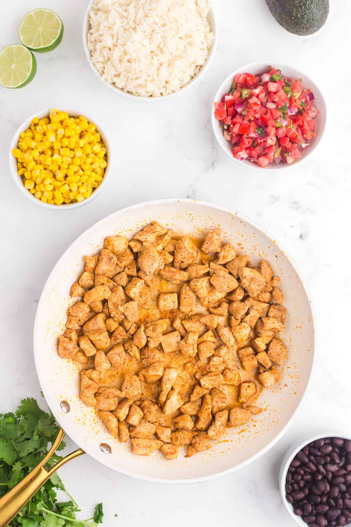 Seasoned and cubed chicken cooking in a large skillet.