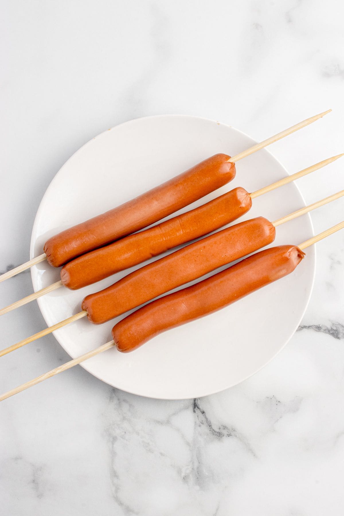 Hot dogs with a wooden skewer in the lengthwise.