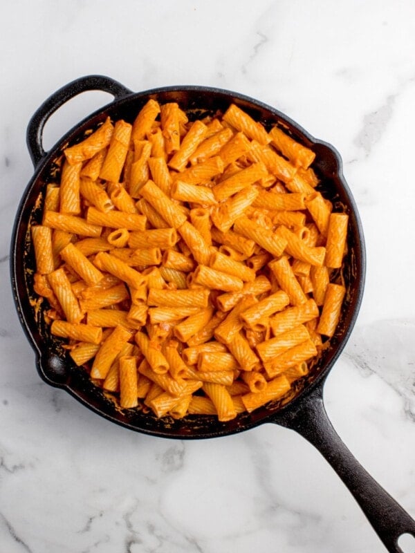 Sauce and pasta are mixed together to complete pasta recipe.
