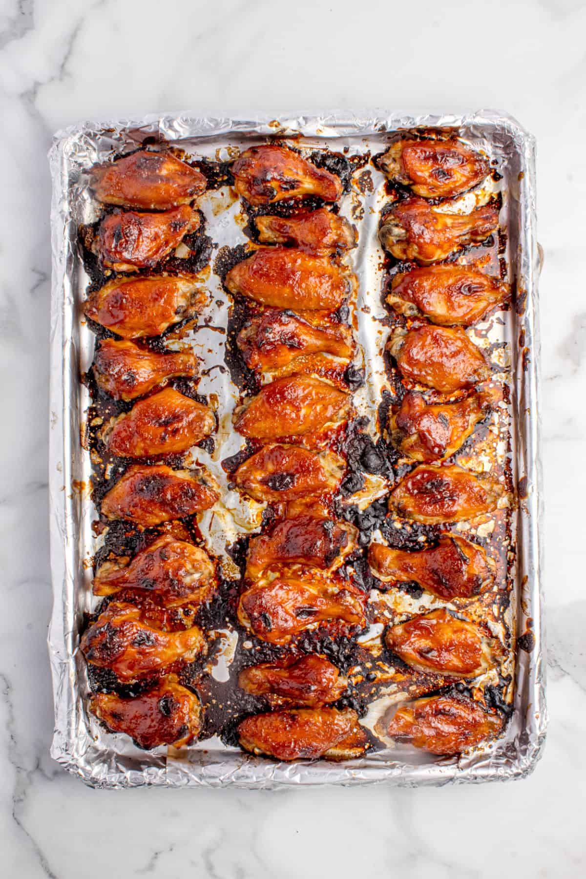 Completed BBQ chicken wings on a foil lined baking sheet.