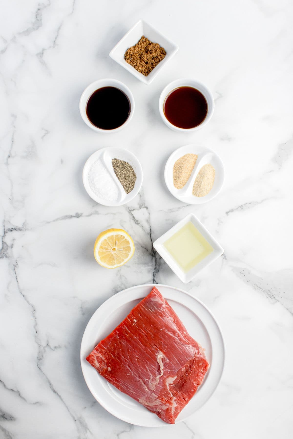 Ingredients for flank steak marinade: vegetable oil, soy sauce, lemon juice, Worcestershire sauce, onion powder, garlic powder, brown sugar, and flank steak.