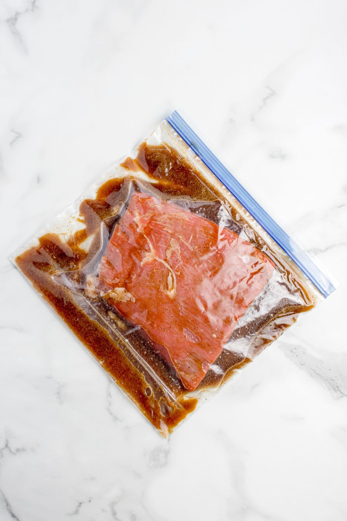 Flank steak marinating in a zip top bag.