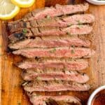 Flank steak that was marinated before grilling sliced against the grain on a cutting board.